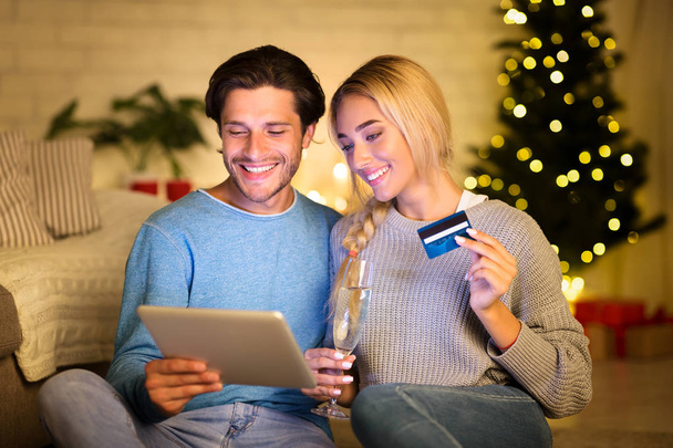 Christmas holiday. Happy couple choosing gifts on tablet - Фото, изображение