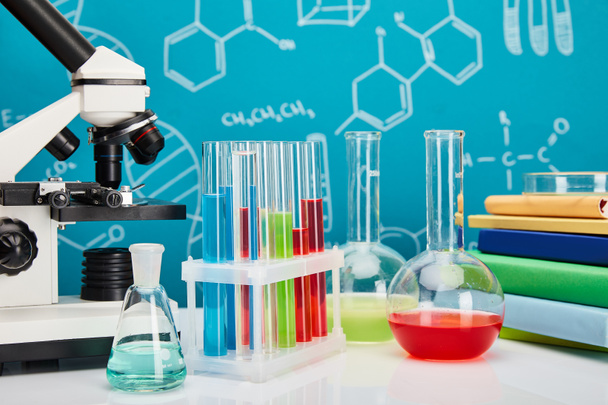 Mikroskop, Bücher, Glas-Reagenzgläser und Kolben mit bunter Flüssigkeit auf blauem Hintergrund mit molekularer Struktur - Foto, Bild