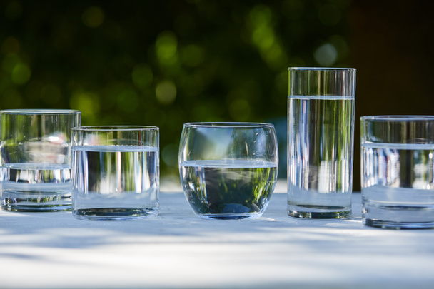 agua dulce transparente en vasos transparentes a la luz del sol sobre mesa de madera
 - Foto, Imagen
