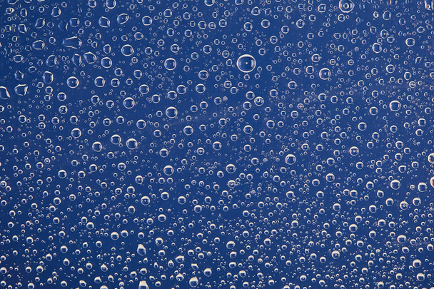 helder transparant water druppels op blauwe achtergrond - Foto, afbeelding