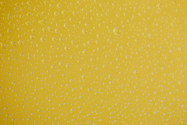 tiszta átlátszó vízcseppek sárga háttérrel - Fotó, kép