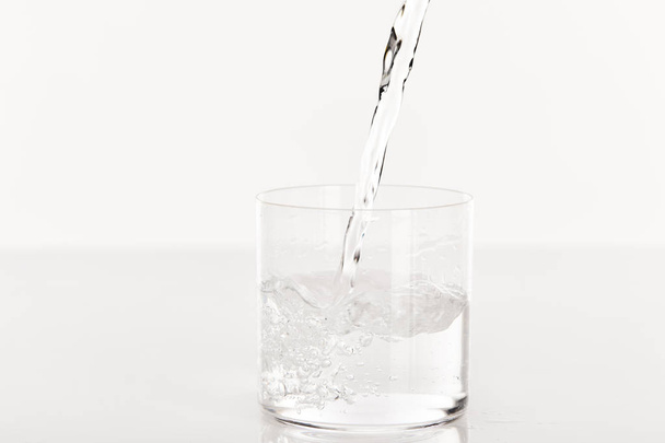 clear fresh water pouring into glass isolated on white - Foto, Bild