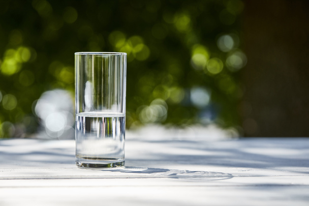fresh clean water in transparent glass at sunny day outside on wooden table - Photo, Image