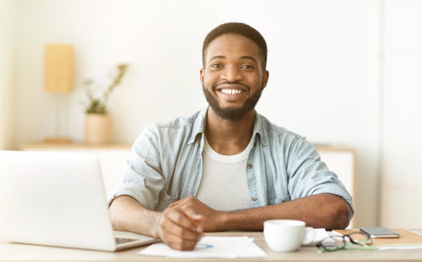 Šťastný africký americký freelancer sedí na pracovišti v domácí kanceláři - Fotografie, Obrázek