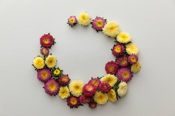 wreath of yellow and purple asters on white background with copy space - Φωτογραφία, εικόνα