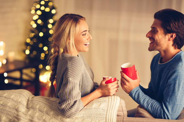 クリスマスイブ。居心地の良い部屋でお茶を飲む幸せなカップル - 写真・画像