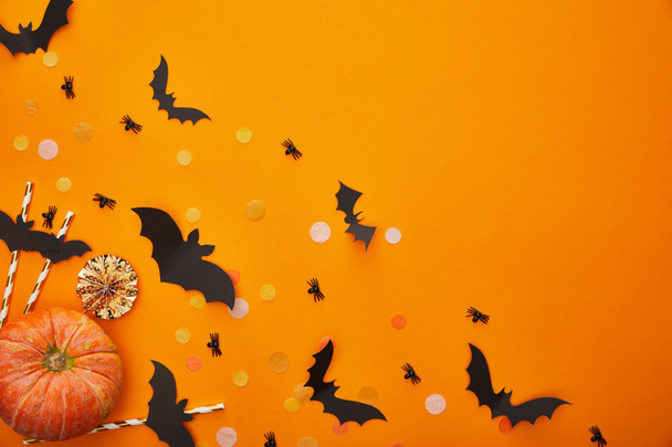 top view of pumpkin, bats and spiders with confetti on orange background, Halloween decoration - Foto, imagen