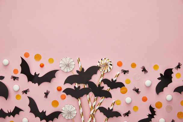 top view of bats and spiders with confetti on pink background, Halloween decoration - Foto, Imagem