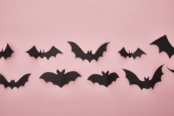top view of black paper bats on pink background, Halloween decoration - 写真・画像