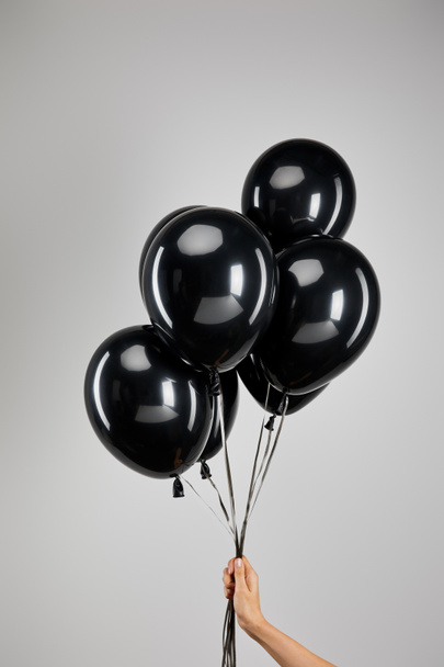 partial view of woman holding bunch of black balloons isolated on grey, black Friday concept - Photo, Image