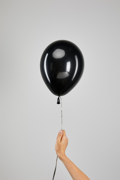 καλλιεργημένη άποψη της γυναίκας που κρατά μαύρο μπαλόνι απομονωμένο σε γκρι, μαύρη έννοια Παρασκευή - Φωτογραφία, εικόνα