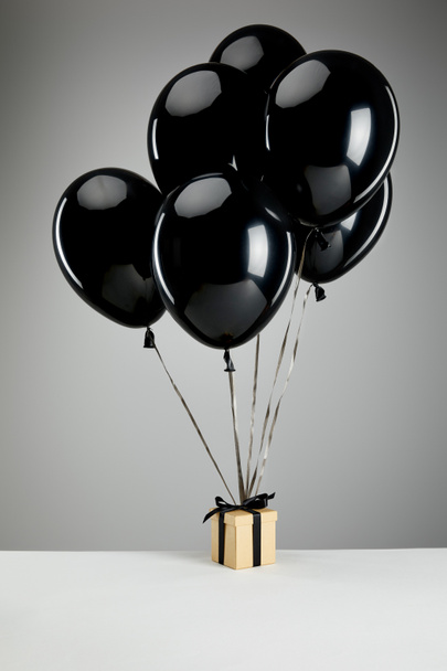 bunch of black balloons with gift box isolated on grey, black Friday concept - Foto, afbeelding