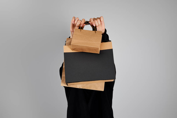 woman with obscure face holding paper shopping bags isolated on grey, black Friday concept - Photo, Image