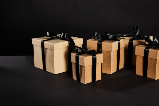 cardboard gift boxes with black ribbons isolated on black, black Friday concept - Foto, Imagen