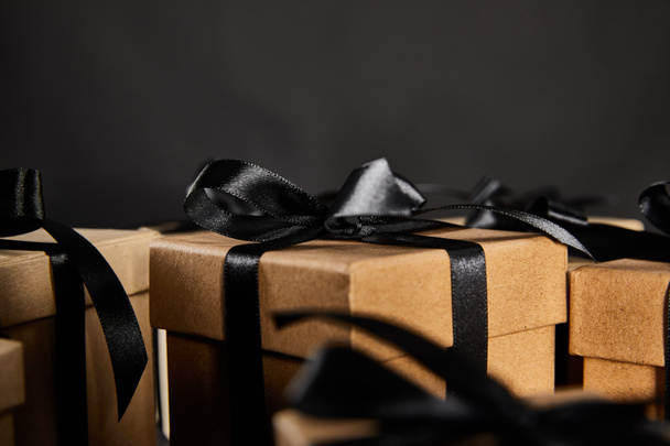close up view of cardboard gift boxes with black ribbons isolated on black, black Friday concept - Fotoğraf, Görsel
