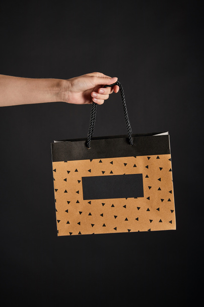 částečný pohled na ženu držící papírové nákupní tašky izolované na černé, černý páteční koncept - Fotografie, Obrázek