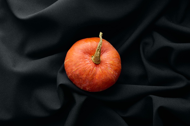 top view of ripe whole colorful pumpkin on black cloth - Zdjęcie, obraz