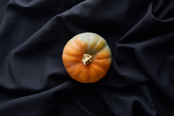 top view of ripe whole colorful pumpkin on black cloth - Foto, afbeelding