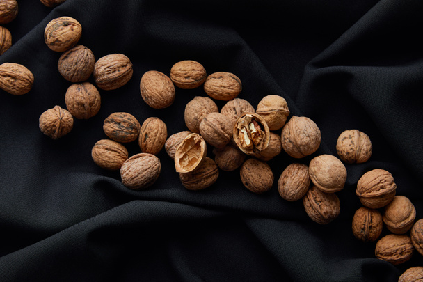top view of brown nuts on black cloth - Fotó, kép