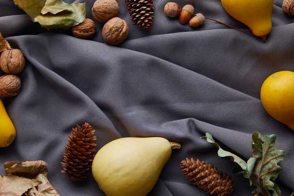top view of ripe pumpkins and autumnal decor on grey cloth with copy space - Foto, afbeelding