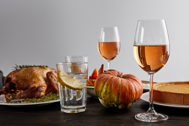 baked pumpkin, grilled turkey, pumpkin pie, glasses with rose wine and lemon water on wooden table isolated on grey - Φωτογραφία, εικόνα