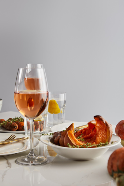 verres avec vin rose, citrouille cuite au four et carottes servis sur table en marbre blanc isolé sur gris
 - Photo, image