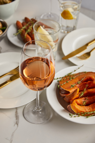 selective focus of glass with rose wine near baked sliced pumpkin of marble table - Fotografie, Obrázek