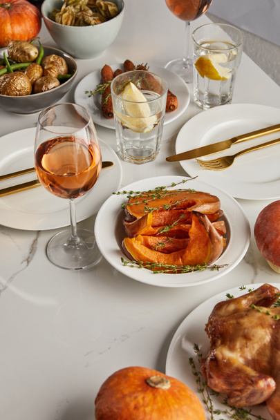traditioneel Thanksgiving diner met gebakken groenten, glazen met rozenwijn en citroenwater op witte marmeren tafel - Foto, afbeelding