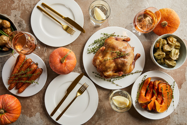 top view of festive dinner with grilled turkey and baked vegetables served on stone surface - 写真・画像