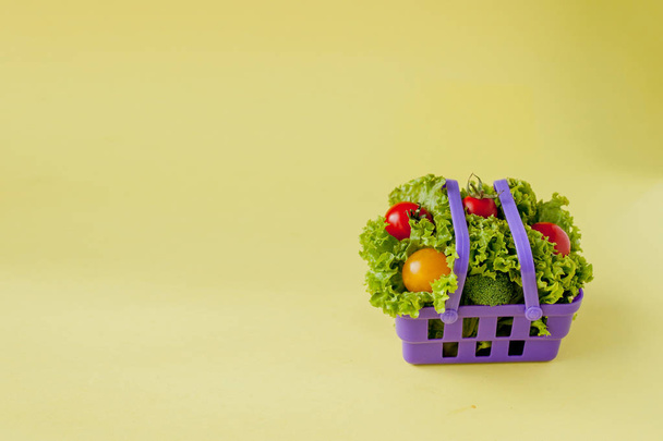 Small Fresh vegetables in basket on yellow background. Food back - Foto, afbeelding