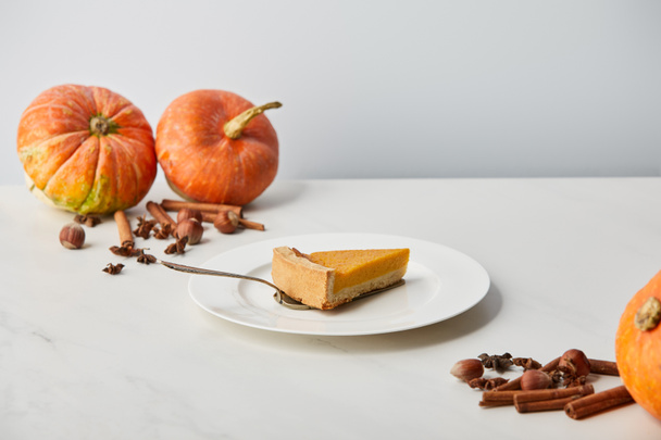 tasty pumpkin pie near while pumpkins and spices isolated on grey - Photo, Image