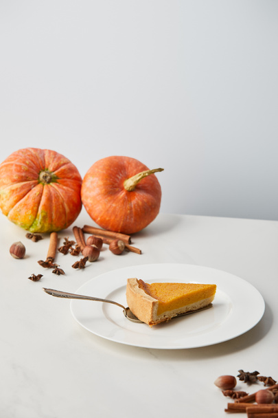 tasty pumpkin pie near while pumpkins and spices isolated on grey with copy space - Photo, Image