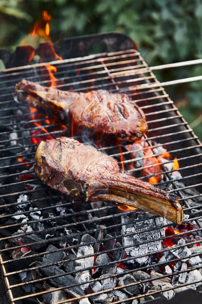 tasty meat grilling on barbecue grid and coal pieces outside  - Foto, imagen