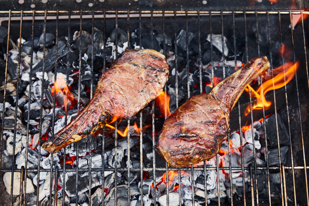 top view of meat grilling on barbecue grid and coal pieces outside  - Foto, Imagem