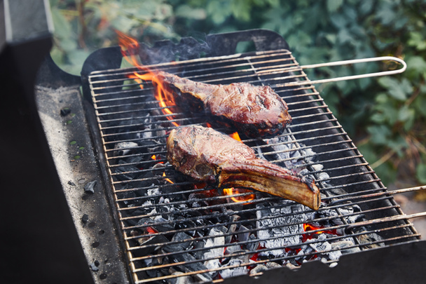 tasty meat grilling on barbecue grid and coal pieces outside  - Foto, imagen