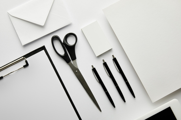 top view of clipboard, pens, business card, paper, envelope, scissors and paper  - Фото, изображение