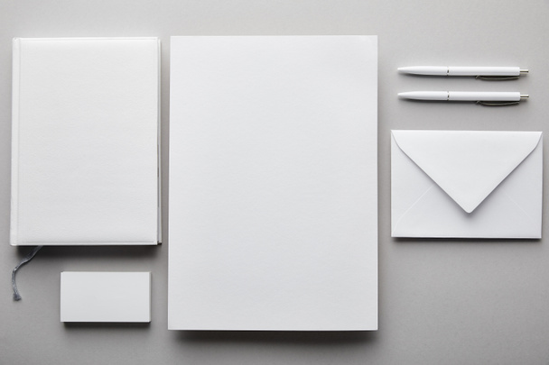 pohled shora na papír, notebook, pera, vizitku a bílou obálku  - Fotografie, Obrázek