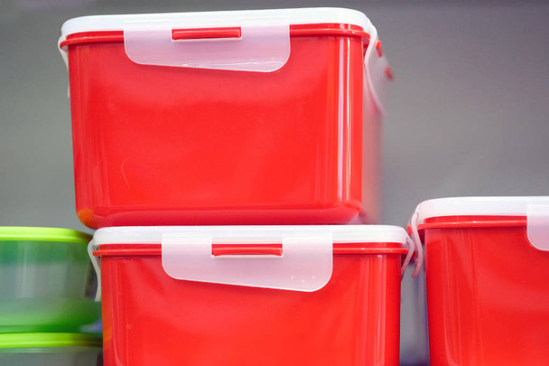 Konyhaélelmiszer-tartályok a polcon. Téglalap alakú műanyag színtálcák. Két doboz piros színű, fehér fedővel az élelmiszer tárolására.. - Fotó, kép