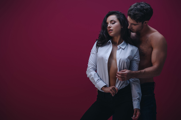 handsome man embracing seductive girl in unbuttoned white shirt on dark background - Photo, Image