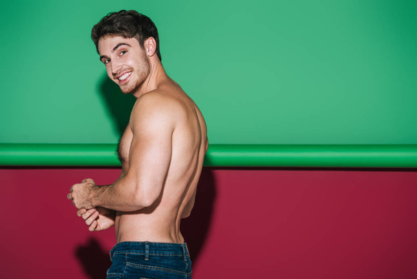 shirtless, sexy man smiling at camera on green and red background - Fotoğraf, Görsel