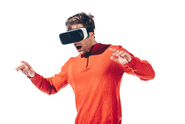 zaszokowany mężczyzna w czerwonym swetrze z zestawem słuchawkowym Virtual reality, odizolowany na białym - Zdjęcie, obraz