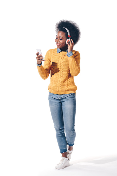smiling african american girl using smartphone with headphones, isolated on white - Фото, зображення