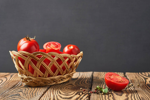 Full wicker basket of tomatoes lies on old rustic wooden table. Space for text - Foto, Imagem
