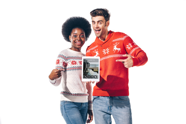 joven pareja interracial apuntando a la tableta digital con tickets aplicación, aislado en blanco
 - Foto, imagen