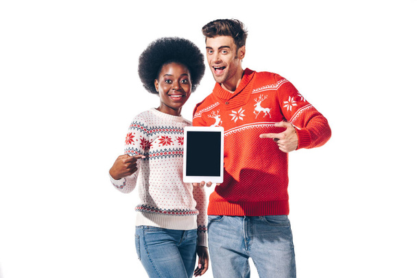jong interraciaal paar gericht op digitale tablet met leeg scherm, geïsoleerd op wit - Foto, afbeelding