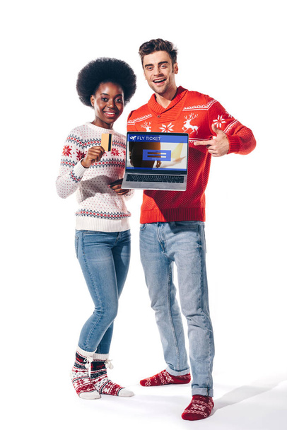 couple multiculturel tenant carte de crédit et ordinateur portable avec site de billets de mouche, isolé sur blanc
  - Photo, image
