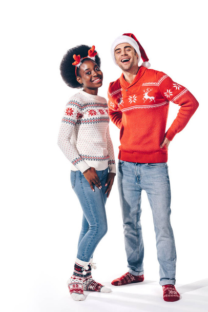 sonriente pareja interracial posando en sombrero de santa y cuernos de ciervo, aislado en blanco
 - Foto, imagen