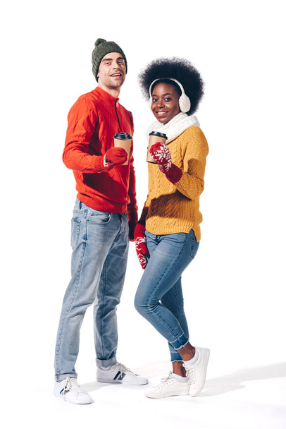 hermosa joven pareja interracial en ropa de invierno sosteniendo café para llevar, aislado en blanco
 - Foto, imagen