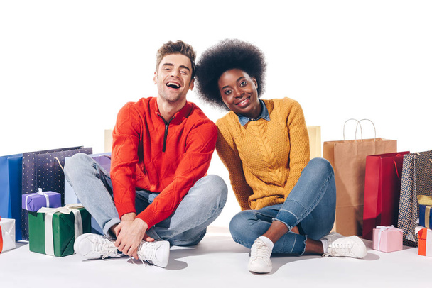 feliz casal interracial com sacos de compras e presentes, isolado no branco
 - Foto, Imagem