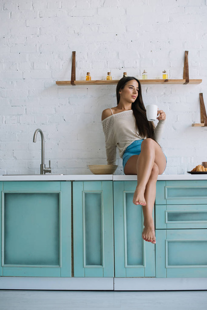hermosa mujer feliz sosteniendo taza de café en la cocina
 - Foto, imagen